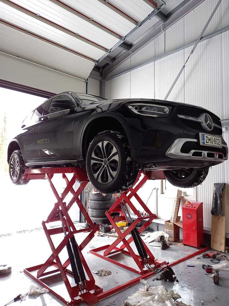 Auto saksinostimella korjaamohallissa